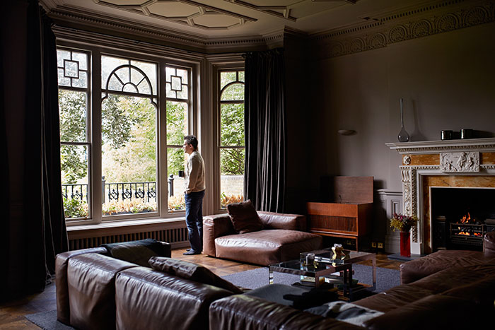 Man looking out an ornate window in his home